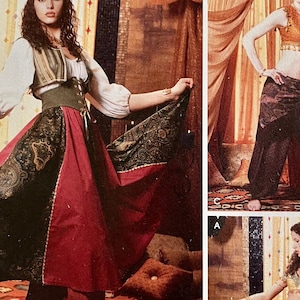 May include: A woman wearing a costume with a green and gold patterned skirt, a red and gold patterned skirt, a white blouse, a green vest, and a brown belt. The costume is inspired by a belly dancer.