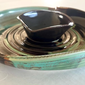 Puede incluir: Una taza de cerámica blanca con un asa negra y el texto "But First, Coffee" en negro, con una fuente de estilo manuscrito. La taza está sobre una superficie blanca.