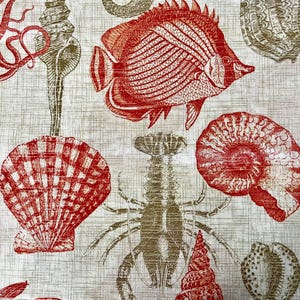 Op de afbeelding: Een witte stof met een rood en bruin zeeleven-patroon. Het patroon bevat een vis, een kreeft, een schelp en een octopus.
