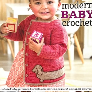 May include: A book titled "modern BABY crochet" featuring a young child wearing a pink crocheted cardigan with a dachshund design. The book cover also includes the text "18 crocheted baby garments, blankets, accessories, and more! * SHARON ZIENTARA"