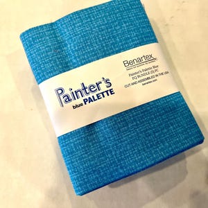 May include: A bundle of blue fabric with a textured pattern, wrapped with a white label. The label reads "Painter's blue PALETTE" and "Painter's Palette Blue PQ BUNDLE (5) PC". The fabric is cut and assembled in the USA.