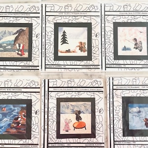 May include: Six square fabric quilt blocks featuring illustrations by Jenn M. Campbell. Each block has a black border with the text Kuspuk Kate and Parka Pete, Anchorage, Alaska. Scenes include a glacier, dog sled, fishing, puffins, blanket toss, and polar bears.