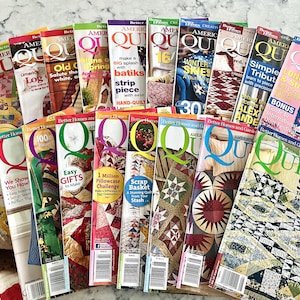 Op de afbeelding: Een verzameling American Patchwork and Quilting tijdschriften in een waaieropstelling. Elke cover toont kleurrijke quiltpatronen, instructieve teksten en titels zoals American Quilt, met diverse naaitechnieken en projecten.