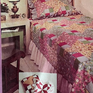 Könnte beinhalten: Ein Patchwork-Quilt- und Kissen-Set mit einem Blumenmuster in Rosa, Grün und Gelb. Das Bett ist mit einem gerüschten Bettrock ausgestattet. Das Bild zeigt auch ein McCall's-Muster.