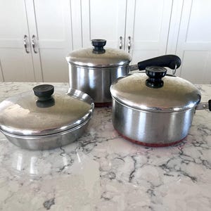Vintage kastruller i rostfritt stål med kopparbotten och lock från Revere Ware från 1801, säljes separat.