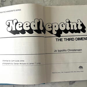 May include: Open book with the title "Needlepoint" in large, black, bubble letters with a white outline. The subtitle reads "The Third Dimension." The author's name is "Jo Ippolito Christensen."