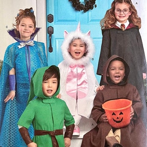 Puede incluir: Cinco niños disfrazados para Halloween. Una niña con un disfraz de princesa azul y morado, una niña con un disfraz de unicornio blanco, un niño con un disfraz de capucha verde, un niño con una túnica marrón con capucha y una niña con una túnica negra con una corbata roja y dorada.