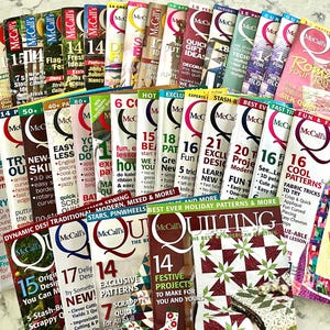 Peut inclure: Une collection de nombreux magazines McCall's Quilting disposés en éventail. Chaque couverture de magazine présente une typographie audacieuse, divers numéros d'édition et des photographies colorées de projets de courtepointe, incluant des motifs floraux.