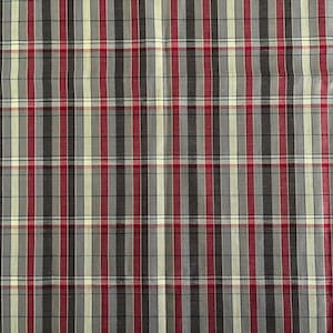 May include: Close-up of a fabric with a plaid pattern. The fabric features vertical and horizontal stripes in red, black, gray, and cream colors. The pattern creates a classic plaid design, suitable for various sewing projects.