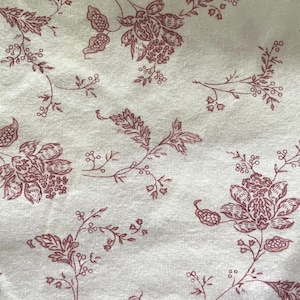 Könnte beinhalten: Ein weißer Stoff mit einem sich wiederholenden Muster aus kleinen roten Blumenmotiven. Die Blumen sind stilisiert und haben einen zarten, Vintage-Look.
