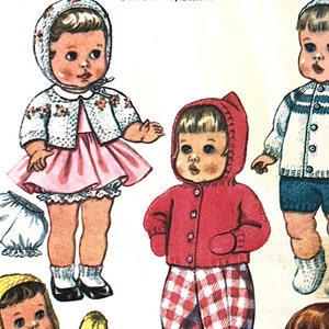 Può includere: Un'illustrazione vintage di quattro bambole che indossano abiti di lana. Le bambole indossano una varietà di abiti, tra cui un vestito rosa con un cardigan bianco, una giacca rossa con pantaloni a quadri, un maglione blu con pantaloncini blu e un cappello giallo con un cardigan bianco.