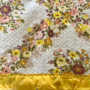 71&quot; wide x 82&quot; long vintage 60&#39;s or 70&#39;s acrylic blanket with satin facings on both ends, bright yellow facings, florals in warm colors.
