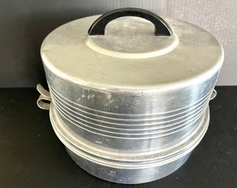 Vintage aluminum Regal Ware double-stacked covered cake and pie carrier with clip on lid, black handle; 10 5/8" in diameter, 7 3/8" tall.