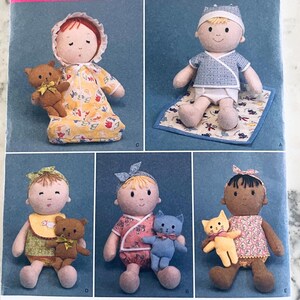 May include: A sewing pattern illustration featuring five fabric dolls with various outfits and accessories. The dolls are shown with small stuffed animals, including teddy bears and cats, wearing bonnets, headbands, and patterned clothing items.