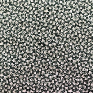 Könnte beinhalten: Nahaufnahme eines Stoffes mit einem sich wiederholenden Muster aus weißen Blumen und abstrakten Formen auf einem dunkelgrünen Hintergrund. Das Design enthält kleine weiße Punkte, die ein strukturiertes Aussehen erzeugen. Die Gesamtästhetik ist vintage und floral.