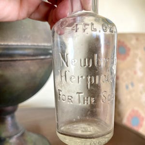 Antieke of vintage Newbros Herpicide voor de hoofdhuid met reliëf van 4 oz. fles met originele dop, gemaakt in de VS, chip aan de rand (zie foto&#39;s).