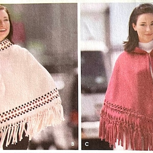 May include: Two ponchos are shown. One is a light pink with a decorative collar and fringe. The other is a red poncho with a hood and fringe. Both ponchos have a similar design, with a fringed hemline and decorative trim.