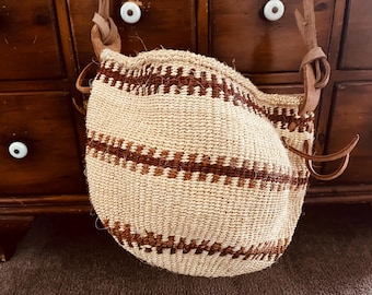 Bolso de mercado africano vintage tejido con sisal y asa de cuero anudada, sin forro; aproximadamente 89 cm de circunferencia en la parte superior central, el asa mide 99 cm de largo.