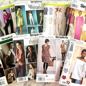 Może przedstawiać: Kolekcja wzorów krawieckich Simplicity z różnymi projektami odzieży. Wzory obejmują różne style, takie jak sukienki, bluzki, kurtki i spodnie. Wzory są wydrukowane na białym papierze z czarnym i zielonym tekstem. Wzory są ułożone w stos na białej powierzchni.