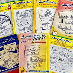 Puede incluir: Una colección de paquetes de transferencias de plancha Aunt Martha's vintage. Los paquetes presentan varios diseños para bordar, incluyendo patrones florales y motivos para fundas de almohadas. Los paquetes son de varios colores, incluyendo amarillo, azul y rosa.