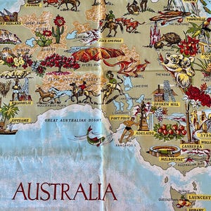 May include: A vintage map of Australia, featuring illustrations of landmarks, animals, and activities. The map is printed on a light beige fabric with a blue ocean border and the word "AUSTRALIA" in large red letters.
