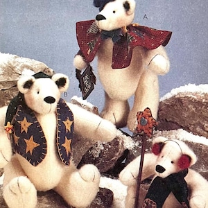 May include: Three plush polar bear dolls with winter accessories. One bear wears a red and green scarf and a blue hat. Another bear has a blue scarf with gold stars. The third bear has red earmuffs and a green scarf.