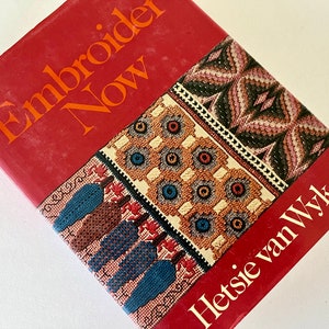 Puede incluir: Un libro rojo titulado "Embroider Now" de Hetsie van Wyk. La portada presenta diseños bordados coloridos.