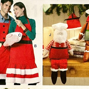 May include: Two red and white Santa Claus aprons with a black belt and white trim. One apron has a white pot holder with red and white checkered pattern. The other apron has a white ruffle trim. Two plush Santa Claus figures wearing red and white checkered shirts and hats. One figure is holding a wooden spoon.