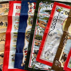 May include: A set of eight tea towels featuring colorful illustrations of different locations in the United Kingdom. The towels are made of cotton and have a white background with red, blue, green, and brown accents. The text on the towels includes the names of the locations, such as "Plymouth", "Torquay", and "Dewlish".