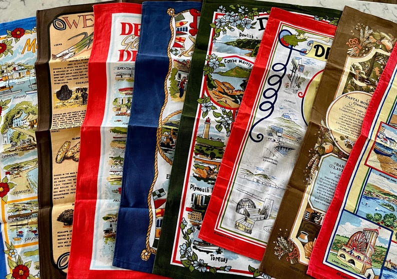 May include: A set of eight tea towels featuring colorful illustrations of different locations in the United Kingdom. The towels are made of cotton and have a white background with red, blue, green, and brown accents. The text on the towels includes the names of the locations, such as "Plymouth", "Torquay", and "Dewlish".