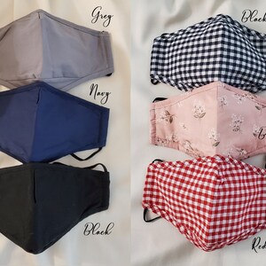 May include: Selection of face masks in different colours and patterns. Includes solid grey, navy, and black masks, plus gingham and floral designs. Each mask has adjustable ear loops for a comfortable fit.