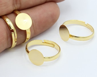 Op de afbeelding: Drie verstelbare ringen in goudkleur met ronde, platte, lege metalen cirkels. De ringen zijn ideaal om bedels, stenen of andere versieringen aan toe te voegen.