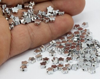 Könnte beinhalten: Ein großer Haufen silberner Metallperlen in Blumenform. Die Perlen haben ein kleines Loch in der Mitte zum Auf fädeln.