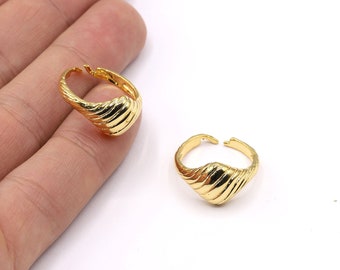 May include: Two gold-toned rings with a textured, wavy design. The rings are open and adjustable.