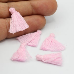 May include: Five small pink fabric tassels, each with a loop at the top for attaching.