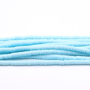 May include: A strand of light blue polymer clay beads. The beads are small and round, and they are strung together on a clear thread.
