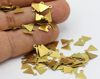 May include: A pile of gold-colored triangle-shaped metal charms with two small loops on each charm. The charms are scattered on a white surface.