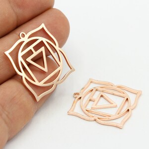 Puede incluir: Dos abalorios de metal de color oro rosa en forma de flor de loto con un cuadrado y un triángulo en el interior. Los abalorios son para la elaboración de joyas.