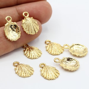 Könnte beinhalten: Ein Set mit sieben goldfarbenen Muschel-Anhängern aus Metall. Die Anhänger sind detailliert und haben eine strukturierte Oberfläche. Sie sind perfekt, um Schmuck oder Bastelarbeiten mit einem Hauch von maritimem Charme zu versehen.