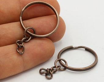 May include: Two bronze key rings with attached chains. The key rings are round and have a smooth finish.