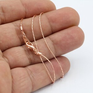 Puede incluir: Un collar de cadena de oro rosa con cierre de mosquetón. La cadena es delicada y tiene un acabado fino y texturizado.