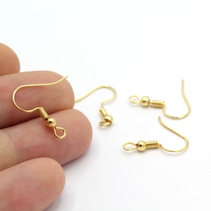 Puede incluir: Cuatro ganchos para pendientes de color dorado con cierre de resorte. Los ganchos son de metal y tienen un acabado liso.
