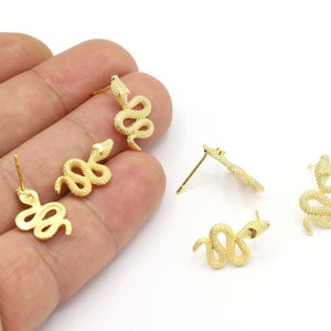 Puede incluir: Cuatro pendientes de serpiente de color dorado. Cada pendiente presenta un diseño de serpiente detallado con una superficie texturizada.