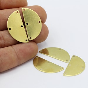 May include: Four brass half-circle shapes with holes for attaching to jewelry or other crafts. The shapes are arranged in a semi-circle pattern.