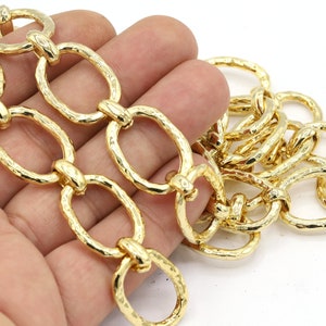 May include: Gold-colored chain with oval links. The chain has a textured, hammered appearance. The links are connected by smaller, round rings. The chain is shown against a white background.