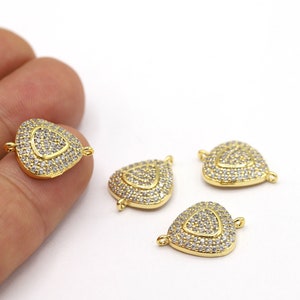 May include: Four gold-tone heart-shaped connector charms with clear cubic zirconia stones. Each charm has two small loops for attaching to jewelry.