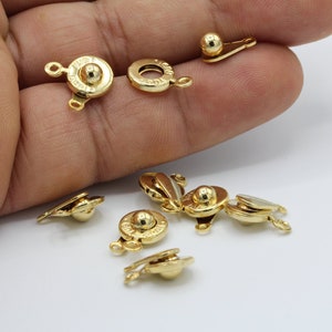 May include: Gold-toned metal clasps with a ball-shaped closure. The clasps are designed for jewelry making and have a decorative, ornate design.