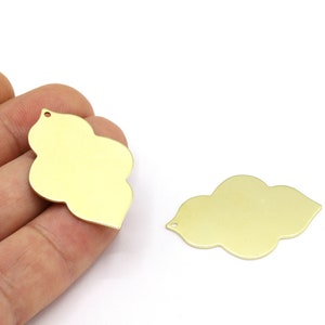 Könnte beinhalten: Zwei goldfarbene Metall-Anhänger in Wolkenform mit einem Loch oben zum Aufhängen.