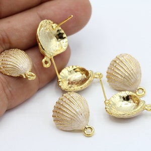 Puede incluir: Cinco abalorios de concha de mar de tono dorado con esmalte blanco. Los abalorios tienen un bucle en la parte superior para sujetarlos a joyas u otras manualidades.