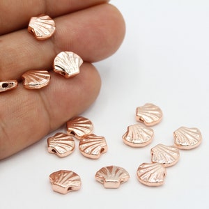 Peut inclure: Un ensemble de breloques en forme de coquillages en métal doré rose. Les breloques sont petites et présentent un design détaillé. Elles sont parfaites pour la fabrication de bijoux ou l'artisanat.